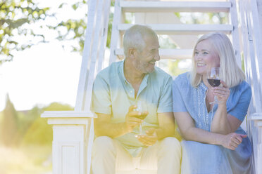 Senior couple drinking wine on summer stairs - CAIF12690