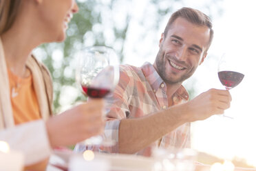 Smiling young couple drinking red wine outdoors - CAIF12708