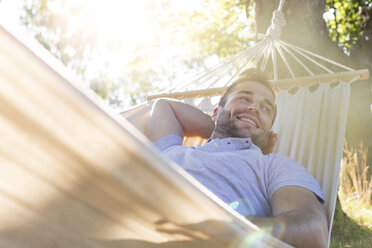 Lächelnder junger Mann entspannt sich in der Sommerhängematte - CAIF12725