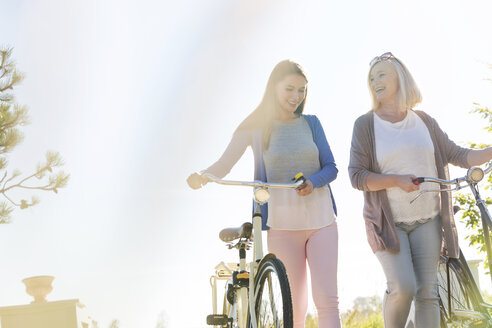 Mutter und erwachsene Tochter gehen mit Fahrrädern spazieren - CAIF12730