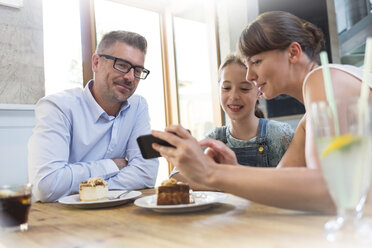 Familie mit Handy isst Dessert am Cafétisch - CAIF12748