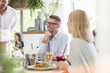 Lächelnder Mann genießt Mittagessen am Cafétisch - CAIF12750