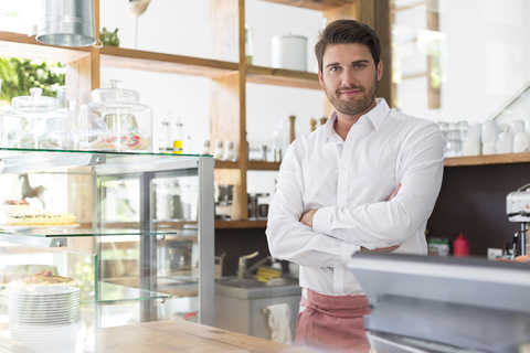 Porträt lächelnder Kellner hinter dem Tresen in einem Cafe, lizenzfreies Stockfoto