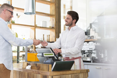 Zahlender Kunde an der Kasse eines Cafés - CAIF12771