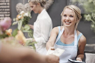 Lächelnder Florist, der von einem Kunden im Blumenladen bezahlt wird - CAIF12783