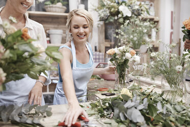 Lächelnde Floristin arrangiert Blumenstrauß im Blumenladen - CAIF12787