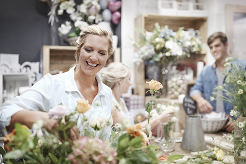 Smiling florist arranging bouquet in flower shop stock photo