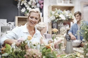 Lächelnde Floristin arrangiert Blumenstrauß im Blumenladen - CAIF12794