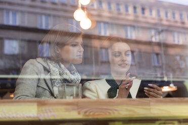 Geschäftsfrau benutzt Handy am Fenster eines Cafés - CAIF12796