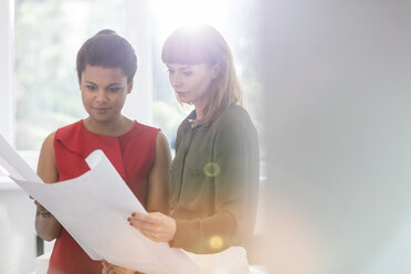 Female architects reviewing blueprints in office - CAIF12817