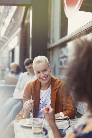 Lächelnde Freunde essen Dessert in einem Straßencafé, lizenzfreies Stockfoto