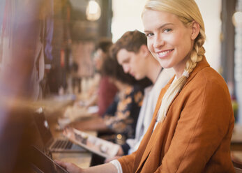 Porträt lächelnde blonde Frau mit digitalem Tablet in einem Café - CAIF12847