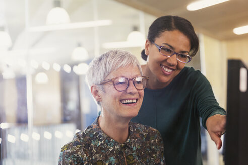 Lächelnde Geschäftsfrauen am Computer im Büro - CAIF12849