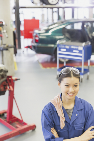 Porträt eines selbstbewussten Mechanikers mit verschränkten Armen in einer Autowerkstatt, lizenzfreies Stockfoto