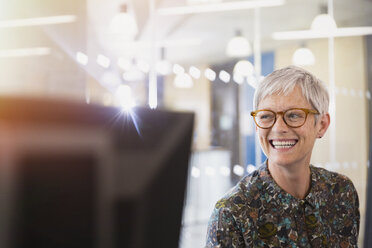 Enthusiastic senior businesswoman looking away in office - CAIF12860