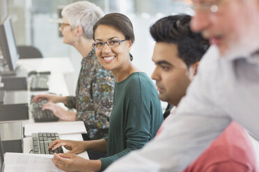 Porträt einer lächelnden Frau am Computer in einem Klassenzimmer der Erwachsenenbildung - CAIF12885