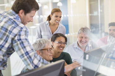 Smiling students at computer in adult education classroom - CAIF12911