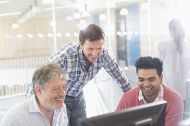 Smiling businessmen working at computer in office - CAIF12933