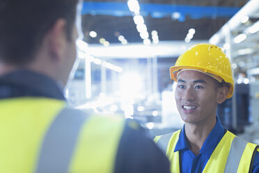 Workers in reflective clothing talking in factory - CAIF12945