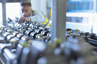 Engineer examining printing press conveyor belt - CAIF12973