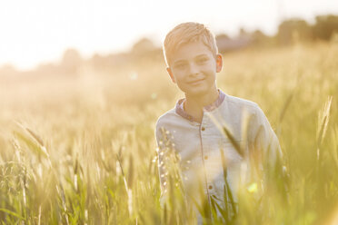 Porträt eines lächelnden Jungen in einem sonnigen ländlichen Weizenfeld - CAIF13049