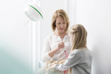 Pediatrician with girl patient and teddy bear in examination room - CAIF13072