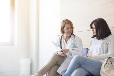 Arzt und Patient bei der Durchsicht der Krankenakte im Foyer der Klinik - CAIF13101