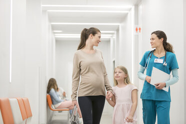 Krankenschwester im Gespräch mit Mutter und Tochter auf dem Krankenhausflur - CAIF13105