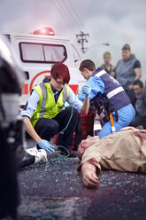 Rescue workers tending to car accident victim in road - CAIF13111