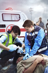 Rescue workers performing CPR and preparing manual resuscitator over car accident victim - CAIF13113
