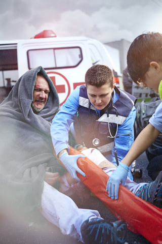 Rettungskräfte bereiten eine Vakuum-Beinschiene für ein Autounfallopfer auf der Straße vor, lizenzfreies Stockfoto