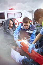 Rescue workers preparing vacuum leg splint on car accident victim in road - CAIF13118