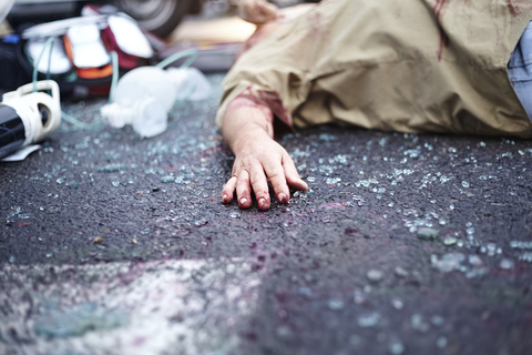 Blutige Hand eines Autounfallopfers auf der Straße zwischen Glasscherben, lizenzfreies Stockfoto