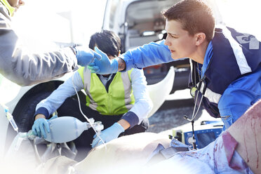 Rescue workers with manual resuscitator over car accident victim in road - CAIF13141