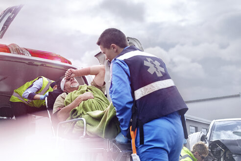 Rescue workers loading car accident victim into back of ambulance - CAIF13145