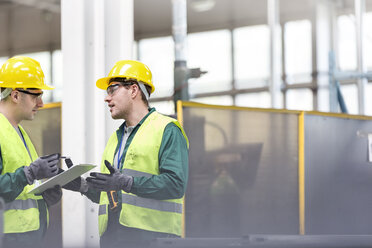 Workers in protective workwear talking with clipboard - CAIF13151