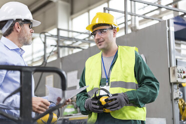 Ingenieur und Arbeiter in Arbeitsschutzkleidung im Gespräch in einer Fabrik - CAIF13154