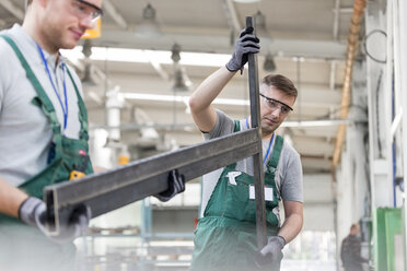 Arbeiter tragen ein Teil in einer Fabrik - CAIF13159