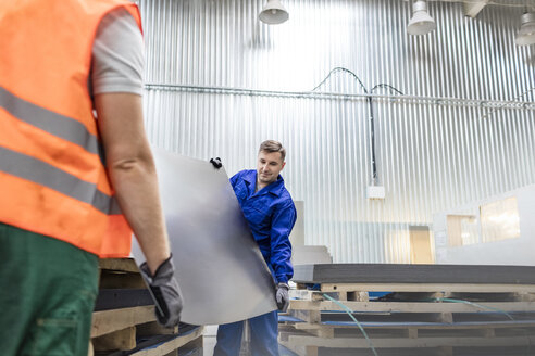 Arbeiter tragen Bleche in einer Fabrik - CAIF13161