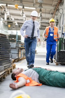 Arbeiter rennen zu einem gefallenen Kollegen, der bewusstlos auf dem Fabrikboden liegt - CAIF13162