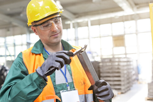 Arbeiter in Arbeitsschutzkleidung bei der Prüfung eines Teils in einer Fabrik - CAIF13166