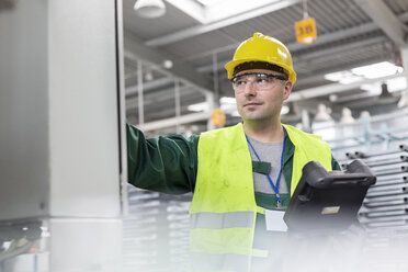 Worker in protective workwear at control panel in factory - CAIF13171