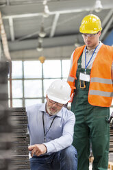 Ingenieur erklärt einem Arbeiter in einer Fabrik Stahlteile - CAIF13175