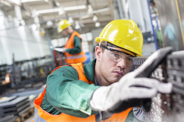 Konzentrierter Arbeiter, der ein Stahlteil in einer Fabrik untersucht - CAIF13179