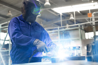 Welder in protective workwear using welding torch in steel factory - CAIF13190