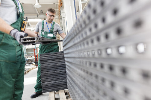 Arbeiter heben Stahlteile in einer Fabrik - CAIF13202