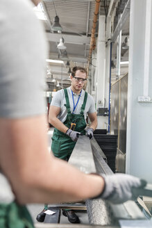 Arbeiter heben Metallteile in einer Fabrik - CAIF13204