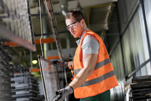 Konzentrierter Arbeiter hält Stahlteil in Fabrik - CAIF13207