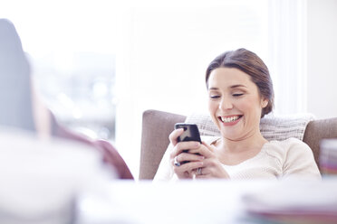 Smiling woman texting with cell phone - CAIF13210