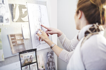 Interior designers discussing blueprints hanging in office - CAIF13231